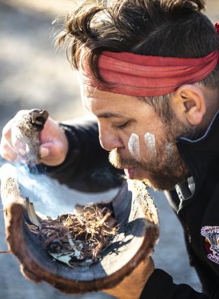 Aboriginal guide Dwayne Bannon-Harrison performing a smoking ceremony during a traditional welcome on a Ngaran Ngaran Culture Awareness tour, South Coast