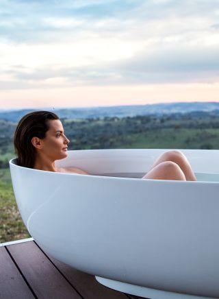 Woman enjoying a relaxing bath with scenic views across the Mudgee countryside from Sierra Escape, Piambong near Mudgee