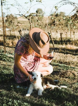 Woman patting the resident wine dog at Blueberry Hill Wines, Rothbury