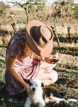 Woman patting the resident wine dog at Blueberry Hill Wines, Rothbury