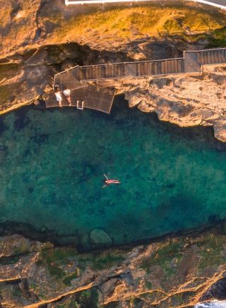 Aerial view of man swimming at the Bogey Hole, Newcastle