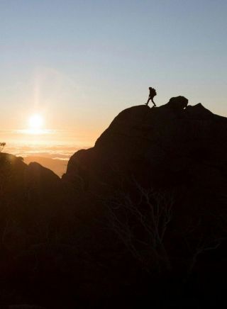 Hiker enjoying a scenic sun set from the top of a mountain at Kosciuszko National Park, Kosciuszko - Credit: Tourism Snowy Mountains