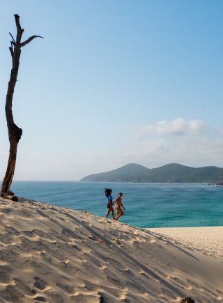 Couple walking down sand dune at One Mile Sand Dune, Forster