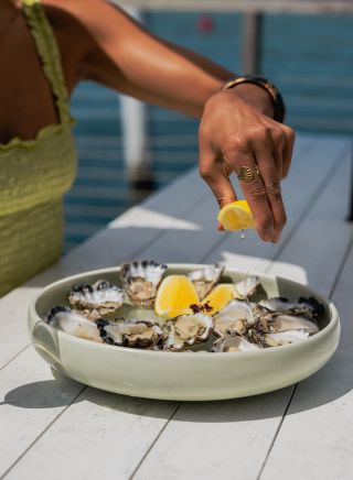 Woman squeezing lemon on oysters, Thirty Three Degrees, Tuncurry