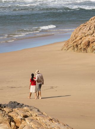 Couple enjoying a walk along Little Bay Beach, Arakoon National Park, Arakoon