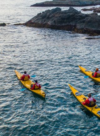 Three kayakers on the water near some rocks looking out to the ocean, Guerilla Bay - Credit: Eurobodalla Coast Tourism