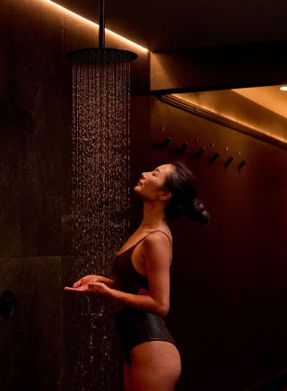 Woman cleanses off in the shower, Aqua Ignis Bathhouse, Blackheath