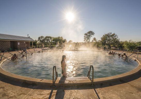 Eine Frau steigt in das dampfende Wasser der Lightning Ridge Bore Baths, Lightning Ridge.