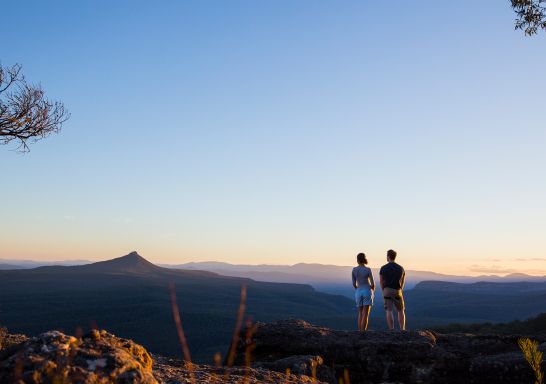 Couple enjoying panoramic views across to Pigeon House Mountain (Aboriginal: Didthul) in Morton National Park