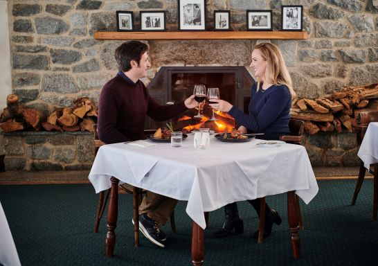 Couple enjoying a meal by the fireplace at Marritz Hotel, Perisher