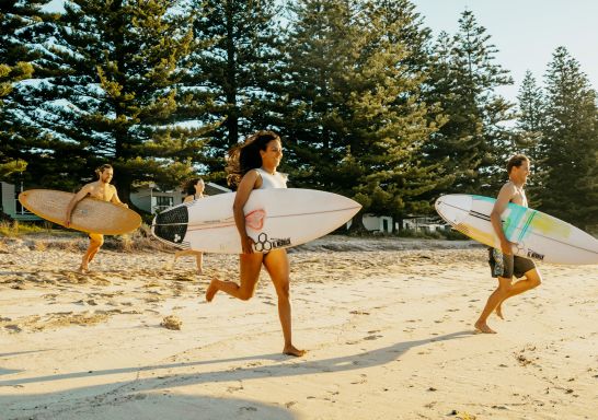 朋友们在南德拉斯 NRMA Murramarang 海滨度假胜地奔向海浪