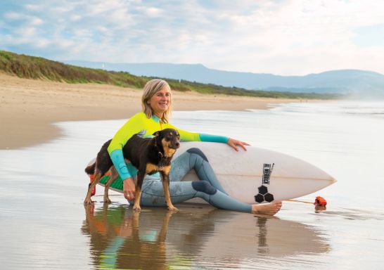 Woman and her pet dog out for a morning surf at Shoalhaven Heads on the South Coast