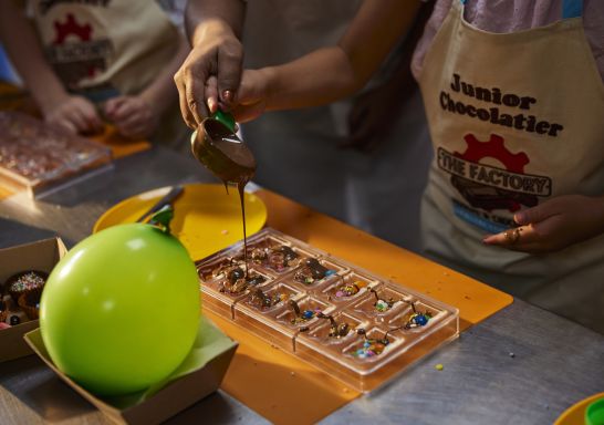 Child pouring chocolate into mould at the Nougat and Chocolate Factory, West Gosford